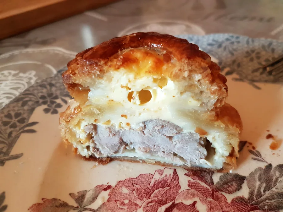 Tourte lorraine coupée montrant la viande marinée en bas et la migaine prise au-dessus