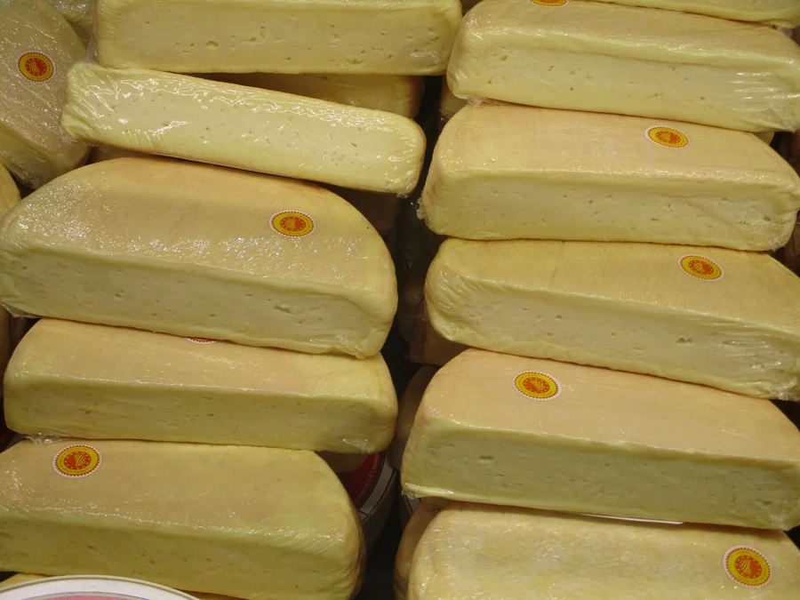 Munsters lorrains entiers empilés sur un étal, croûte orangée et pastille d'appellation